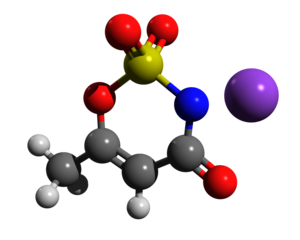 alt: Molekula Acesulfamu K. Zdroj Wikimedia Commons, autor NZLS11, licence Creative Commons CC0 1.0 Universal Public Domain Dedication. Černě atomy uhlíku, bíle vodíku, červeně kyslíku, modře dusíku, žlutě síry. Fialově je znázorněn kation draslíku.