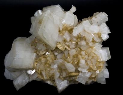 alt: Dolomit (větší bílé krystaly) a magnezit (menší žlutohnědé krystaly) z naleziště Azcárate ve Španělsku. Zdroj Wikimedia Commons, autor Didier Descouens, licence Creative Commons Attribution 3.0 Unported.