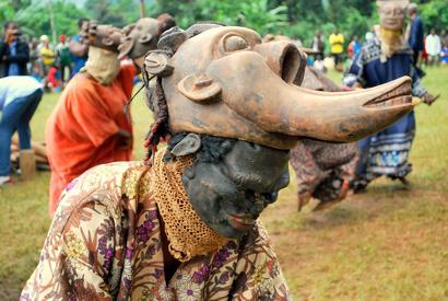 alt: Tanečníci dju dju a jejich masky neodmyslitelně patří k tradicím lidí z lesa.