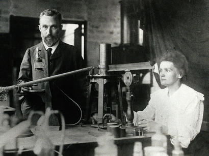 alt: Pierre a Marie Curieovi v laboratoři. Zdroj Wikimedia Commons, volné dílo / public domain.