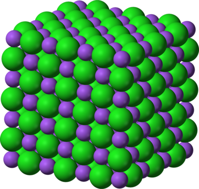 alt: Uspořádání atomů v krystalu chloridu sodného. Fialově jsou znázorněny sodné ionty, zeleně chloridové ionty. Zdroj Wikimedia Commons, autor Benjah-bmm27, volné dílo / Public Domain.