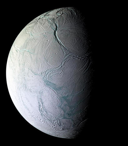 alt: Srpek malého Saturnova měsíce Enceladu, vyfotografovaný sondou Cassini roku 2008. Vpravo dole jsou slavné tygří pruhy poblíž jižního pólu Enceladu, kde dochází k největší geologické aktivitě včetně častých gejzírů. Pod ledovou kůrou měsíce se ukrývá globální vodní oceán. Kredit: NASA/JPL/Space Science Institute.