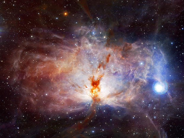 alt: Mlhovina Plamínek (NGC 2024), součást velkého molekulárního mračna v souhvězdí Orion. Podmínky uvnitř těchto mračen umožňují tvorbu molekul vodíku, oxidu uhelnatého a dalších látek. Snímek byl pořízen v infračervené oblasti spektra a obarven umělými barvami. Zdroj Wikimedia Commons, kredit ESO/J. Emerson/VISTA a Cambridge Astronomical Survey Unit, úpravy Jan Kolář, licence CC BY 4.0.