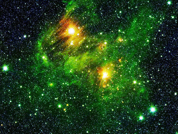 alt: Ilustrační obrázek: Organické látky ze skupiny polycyklických aromatických uhlovodíků *(zeleně)* v kosmickém mračnu, z něhož se rodí nové hvězdy. Snímek ze Spitzerova vesmírného dalekohledu je obarven umělými barvami; polycyklické aromatické uhlovodíky ve skutečnosti „svítí“ v infračervené oblasti spektra. Zdroj Wikimedia Commons, autor NASA / JPL-Caltech / 2MASS / SSI / University of Wisconsin – Spitzer, volné dílo / Public Domain.