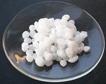 alt: Pevný hydroxid sodný ve formě peciček. Zdroj Wikimedia Commons, autor Walkerma