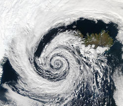 alt: Tlaková níže nad Islandem se otáčí proti směru hodinových ručiček v důsledku rovnováhy Coriolisovy síly a rozložení tlaku. Foto: NASA